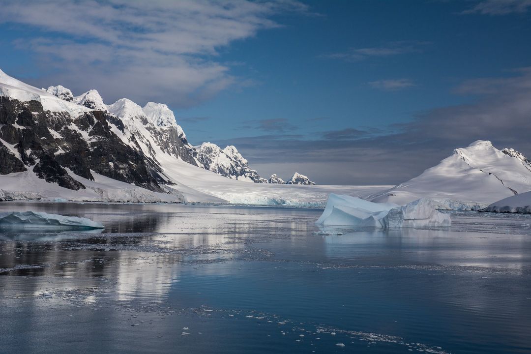 Antarctic landscape photo featuring ice, water and mountains.